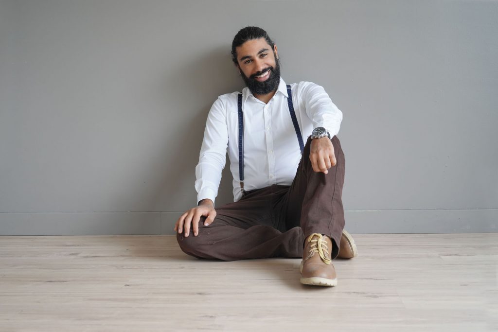 Guy sitting on the floor while wearing suspenders