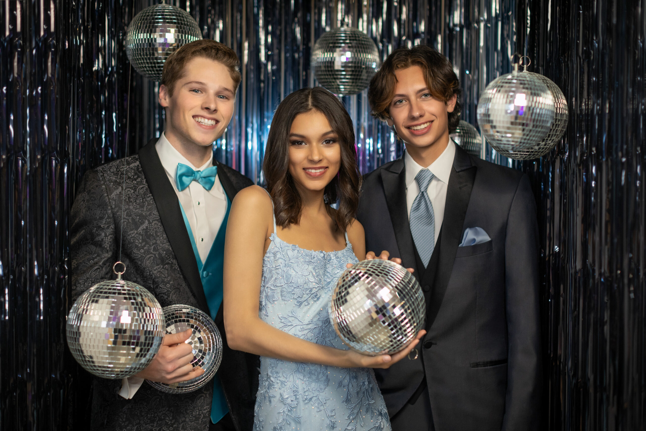 two men and one woman in formal attire with disco balls as a background