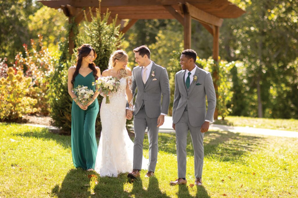 bride and groom walking with groomsman and bridesmaid in a garden setting - wedding tips