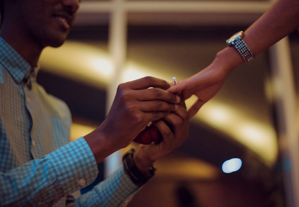 Ultimate Wedding Checklist for Grooms - Proposal shot of man putting a ring on a woman's finger