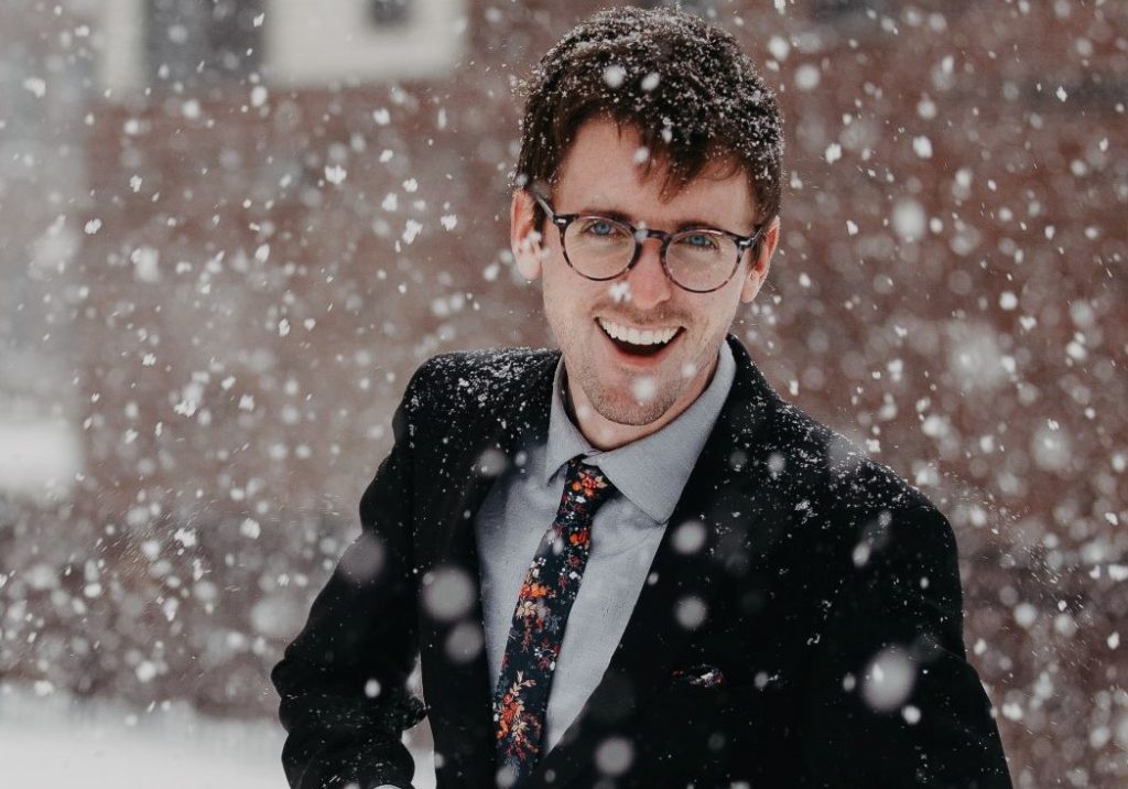 Men's Holiday Style Guide - A stylish man dressed in a suit standing in the snow