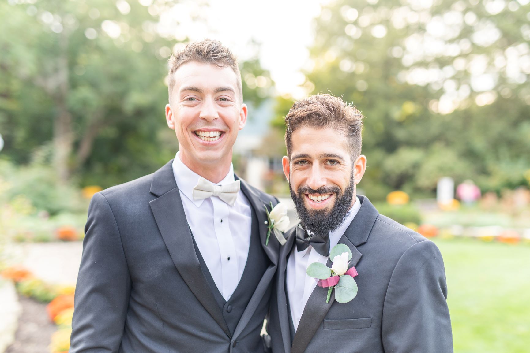 groom standing next to his groomsman wearing matching black tuxedos