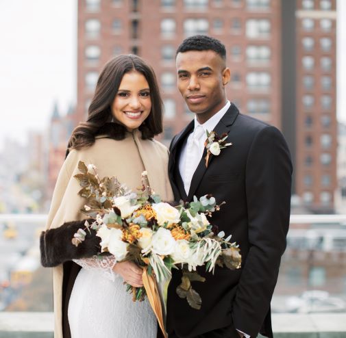 bride with shawl and groom in black tux on rooftop