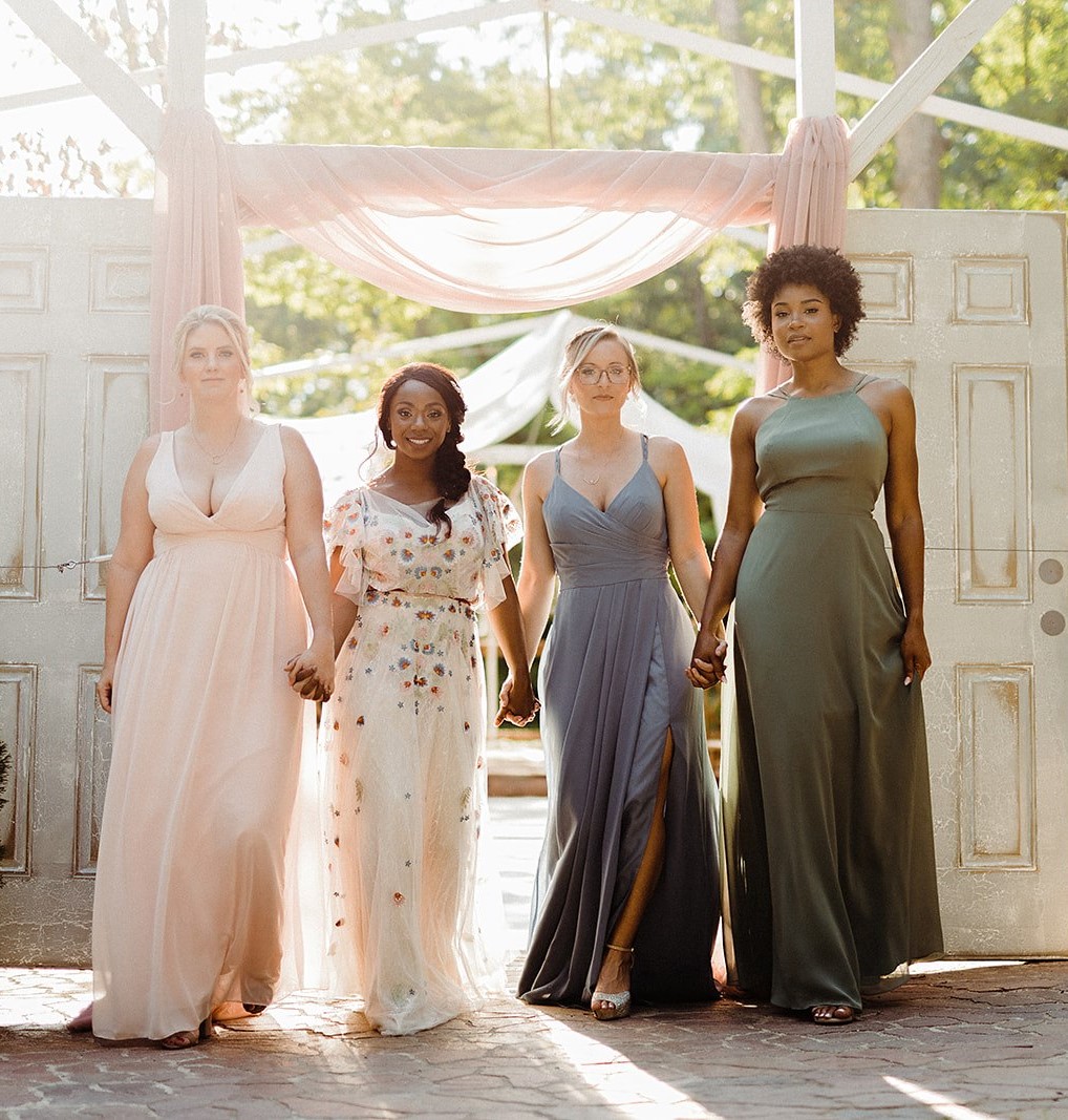 women in different colored dresses that match spring wedding colors; light pink, dusty blue, sage green and white with multi colored flowers