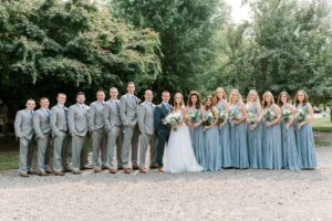 bride and groom with wedding party, groomsmen in grey suits, bridesmaids in dusty blue dresses