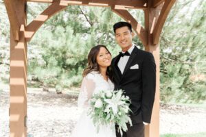 bride and groom standing next to each other, groom in black tuxedo with black bowtie