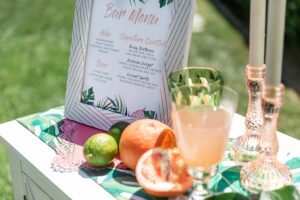 Tropical drinks, fruit, menu on table in sun. Trending Wedding Bar Ideas