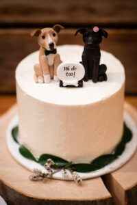 wedding cake with 2 dog toppers with a sign that reads we do too