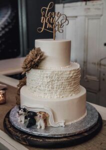 wedding cake with 3 dogs peeking out of icing