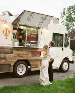 Bride and groom standing in front of food truck. Trending Wedding Ideas.