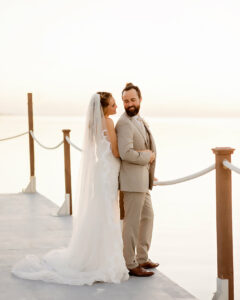 bride in white dress and groom in tan suit on boardboalk