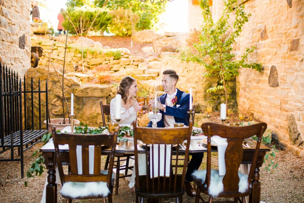 bride and groom sitting at the head table surrounding by a rock grotto and green landscape