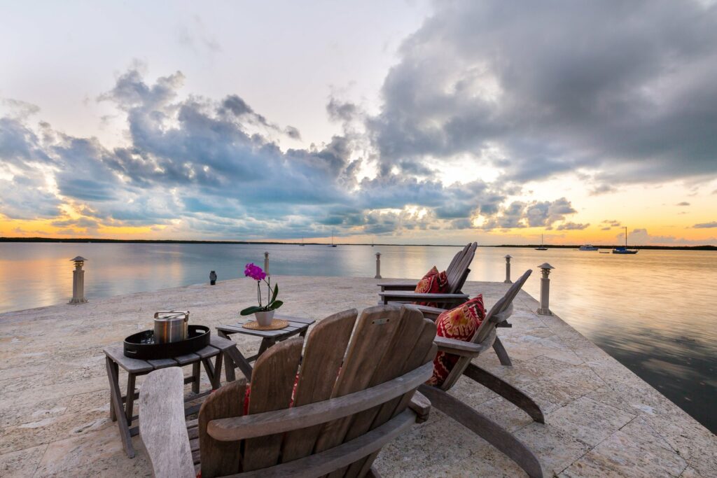 adirondack chairs overlook the water at sunset on the pier