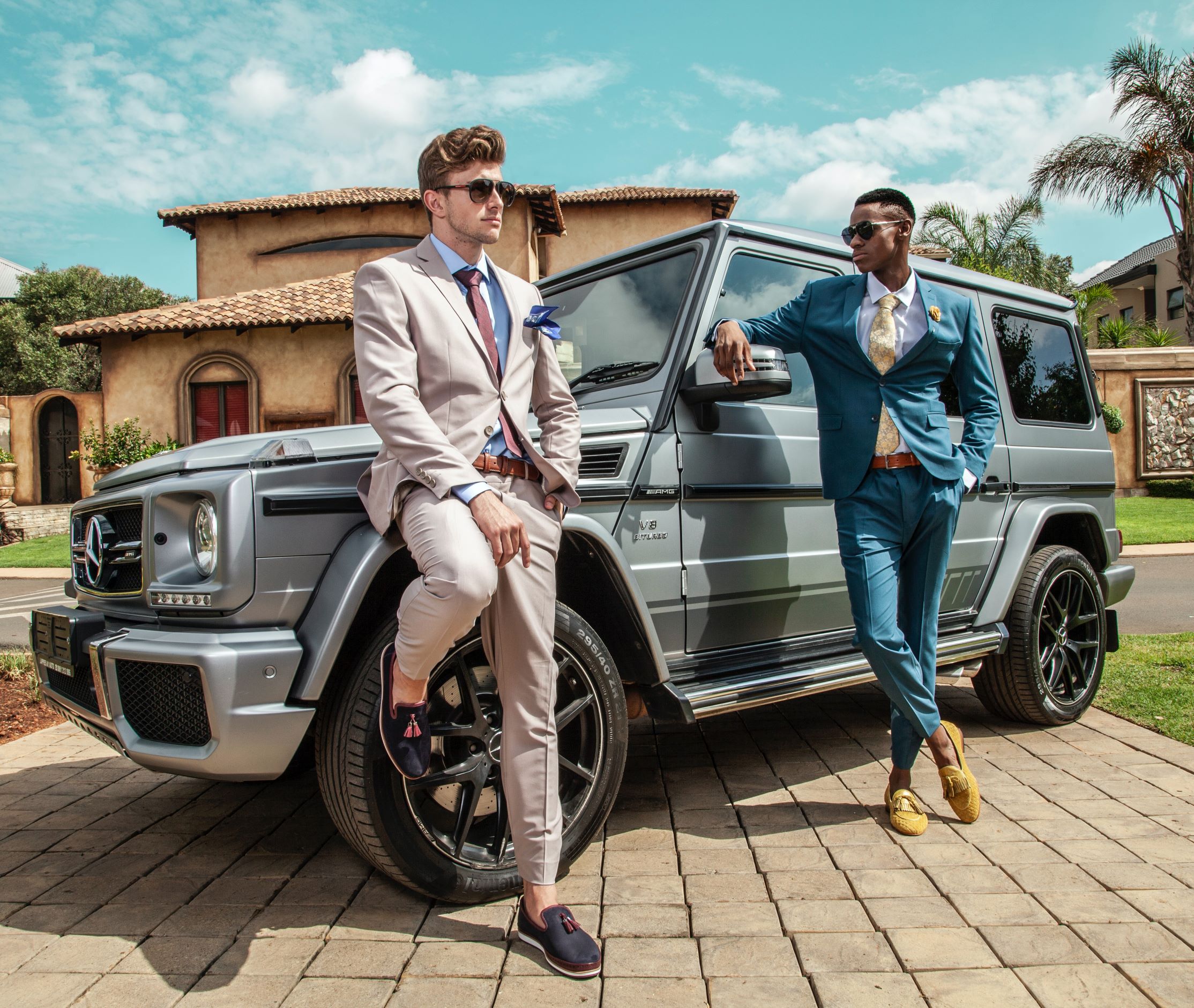 two guys in suits standing in front of mercedes suv