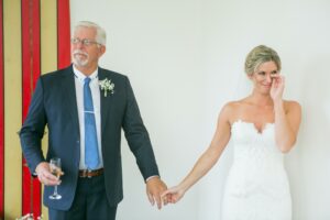 bride crying while holding father's hand at wedding