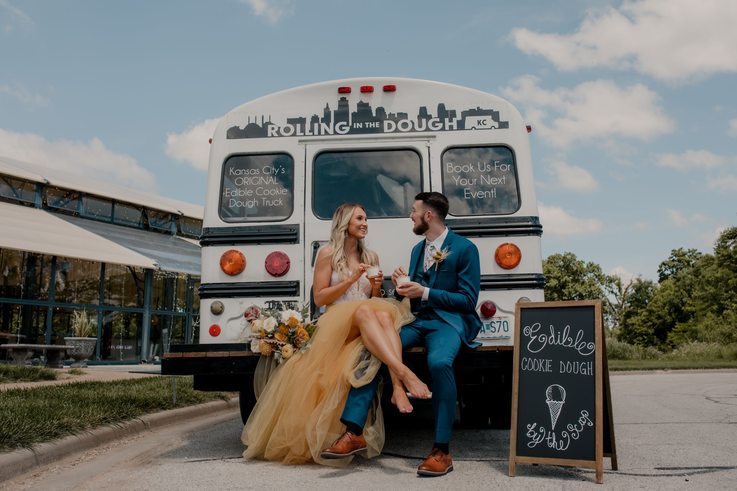 bride and groom sitting on back of mini bus that serves edible cookie dough