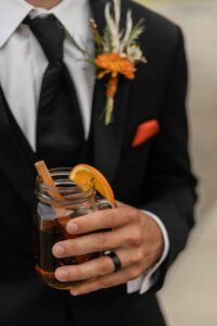 guy in black tuxedo holding hot toddy drink