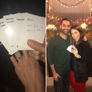 woman with holding cards from the game Cards Against Humanity and the guy and girl who just got engaged standing in front of a fireplace