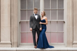 prom guy in steel grey suit and prom girl in navy dress posing for prom photo