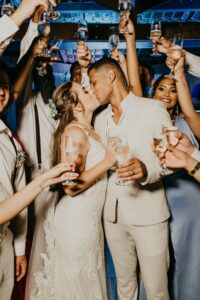 bride and groom kissing, surrounded by wedding party