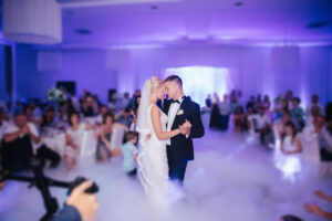 bride and groom doing their first dance at their wedding, guests blurred out in background