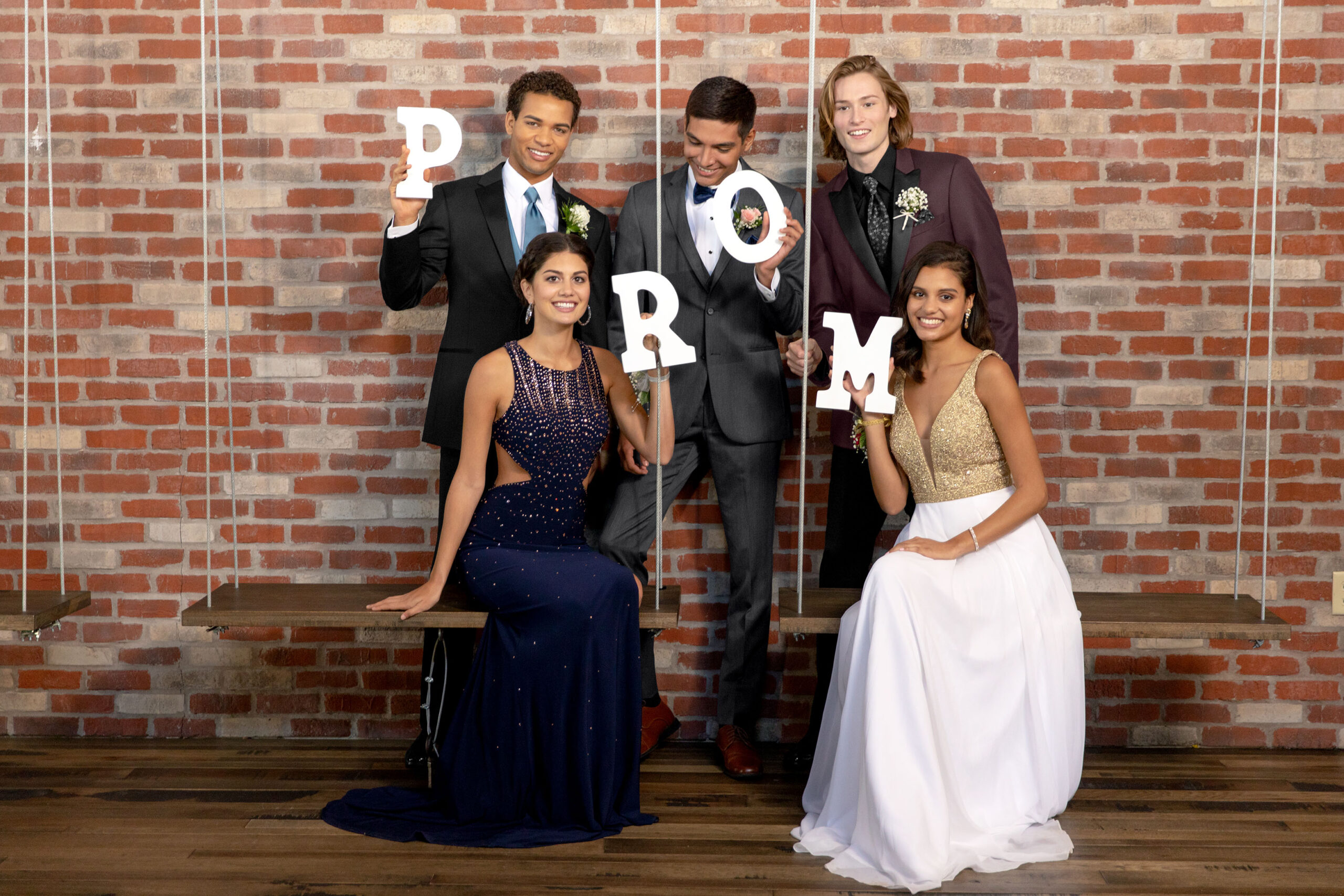 group of guy and girl friends holding letters spelling prom and they are dressed up for prom