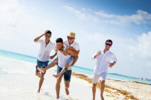 Group of young men running on beach, two are a engaged couple