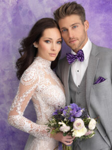 bride and groom next to each other, bride in white dress, groom in grey suit with striped purple bowtie and pocket sqaure