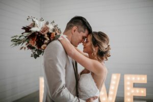 bride and groom hugging, foreheads touching. Bride holding bouquet