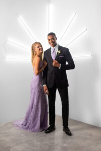 high school kid wearing black suit with light purple tie standing next to homecoming date who is wearing a light purple dress