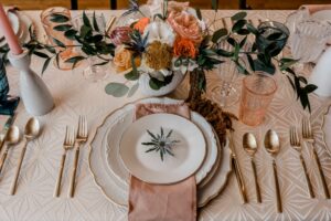 table setting with colored drinkware, floral arrangement with shades of oranges, 