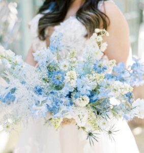 bride holding bouquet of light blue and white flowers for 2023 wedding