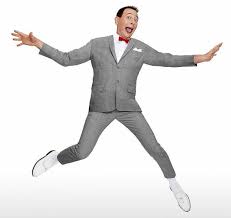 Pee-Wee herman jumping in the air, wearing grey suit, red bow tie, white shoes