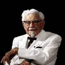 Colonel Sanders from Kentucky Fried Chicken, wearing white suit, black string tie.