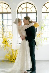 bride and groom looking at each other, hugging. Bright yellow flowers in the background