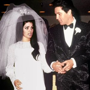 Elvis Presley and Pricilla on their wedding day. Pricilla in wedding dress, Elvis in black paisley suit