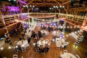 above view of wedding reception venue with tables and chairs, string lights lighted above them