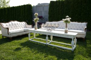 white couches next to a white table at a wedding reception for guests to mingle and hang out
