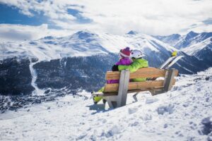 couple sitting on bench a top of a mountain for winter honeymoon