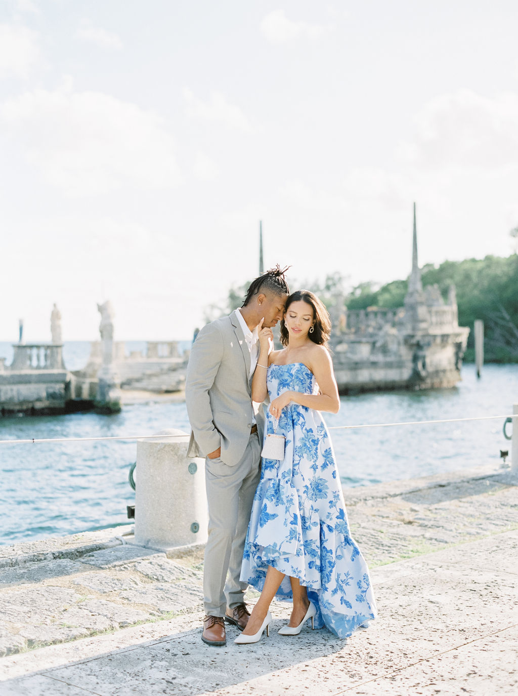 couple on a cobblestone pathway with water behind them