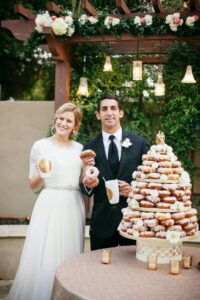 bride and groom in front of a donut tower at their wedding