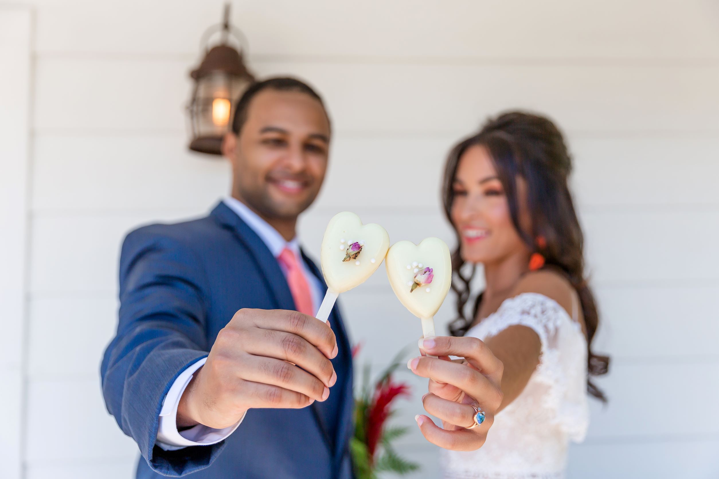 groom in blue tux, bride in wedding dress, holding heart shaped cake-pops