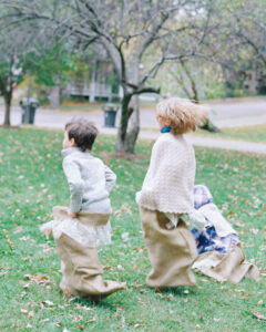 entertain kids at the wedding; kids at a wedding, outside doing a sack race