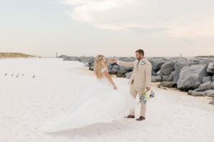 bride and groom wearing a tan suit dancing on a white sandy beach for a destination wedding