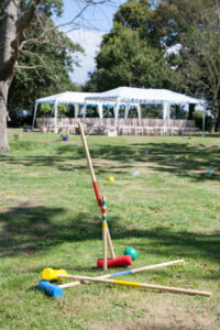 lawn games - croquet set at an outdoor wedding with the white tent seen in the background