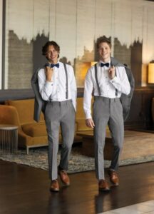 prom trends - two guys wearing matching grey pants, white shirts, bow ties, and suspenders