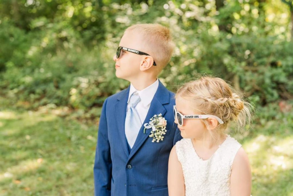 Ring bearer and flower girl posing with sunglasses.