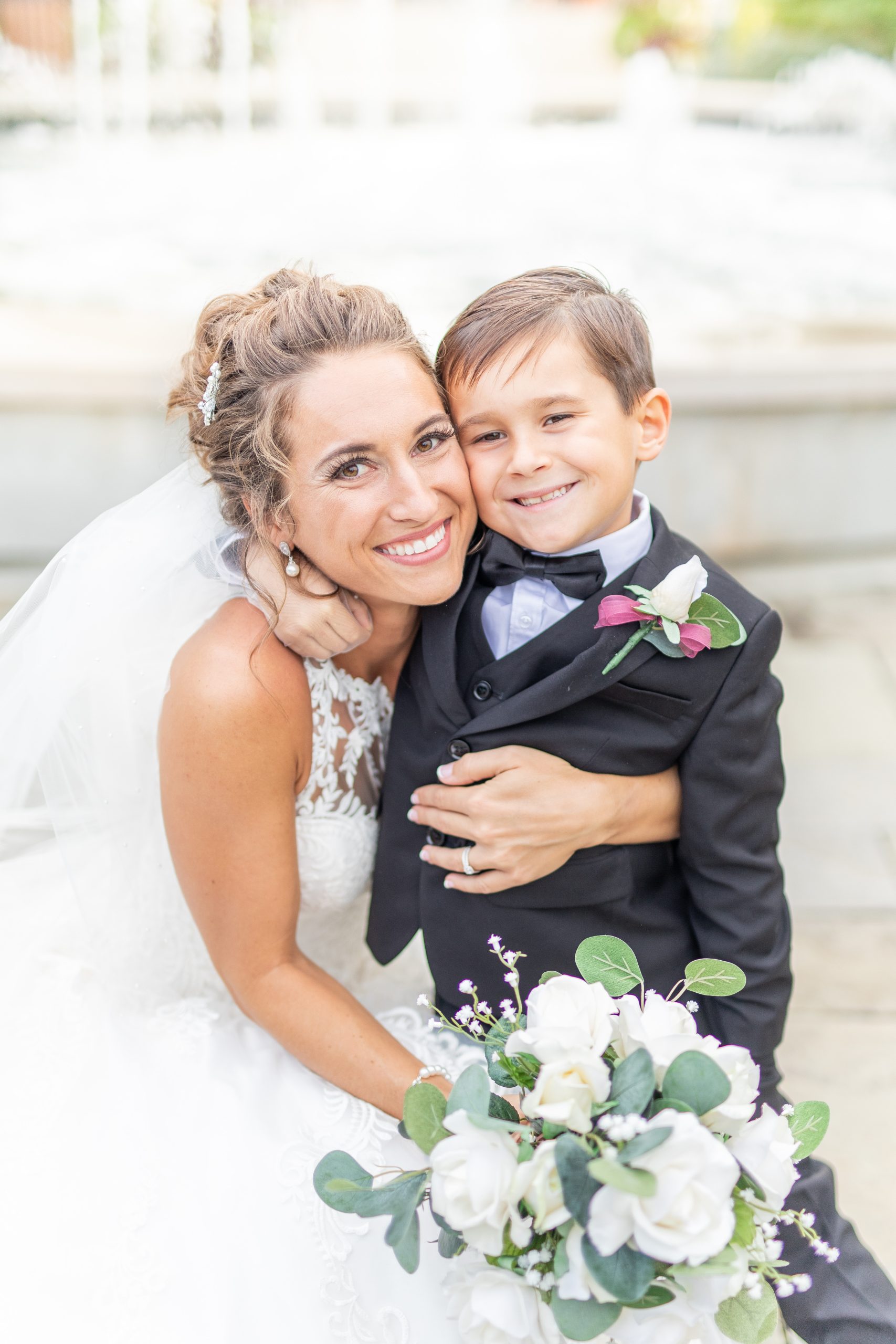 Bride hugging ringbearer posing for a picture