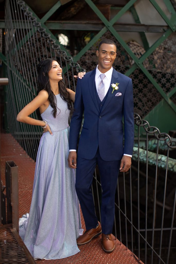 Prom couple smiling dressed in a dusty lavender dress and blue suit with matching lavender accessories