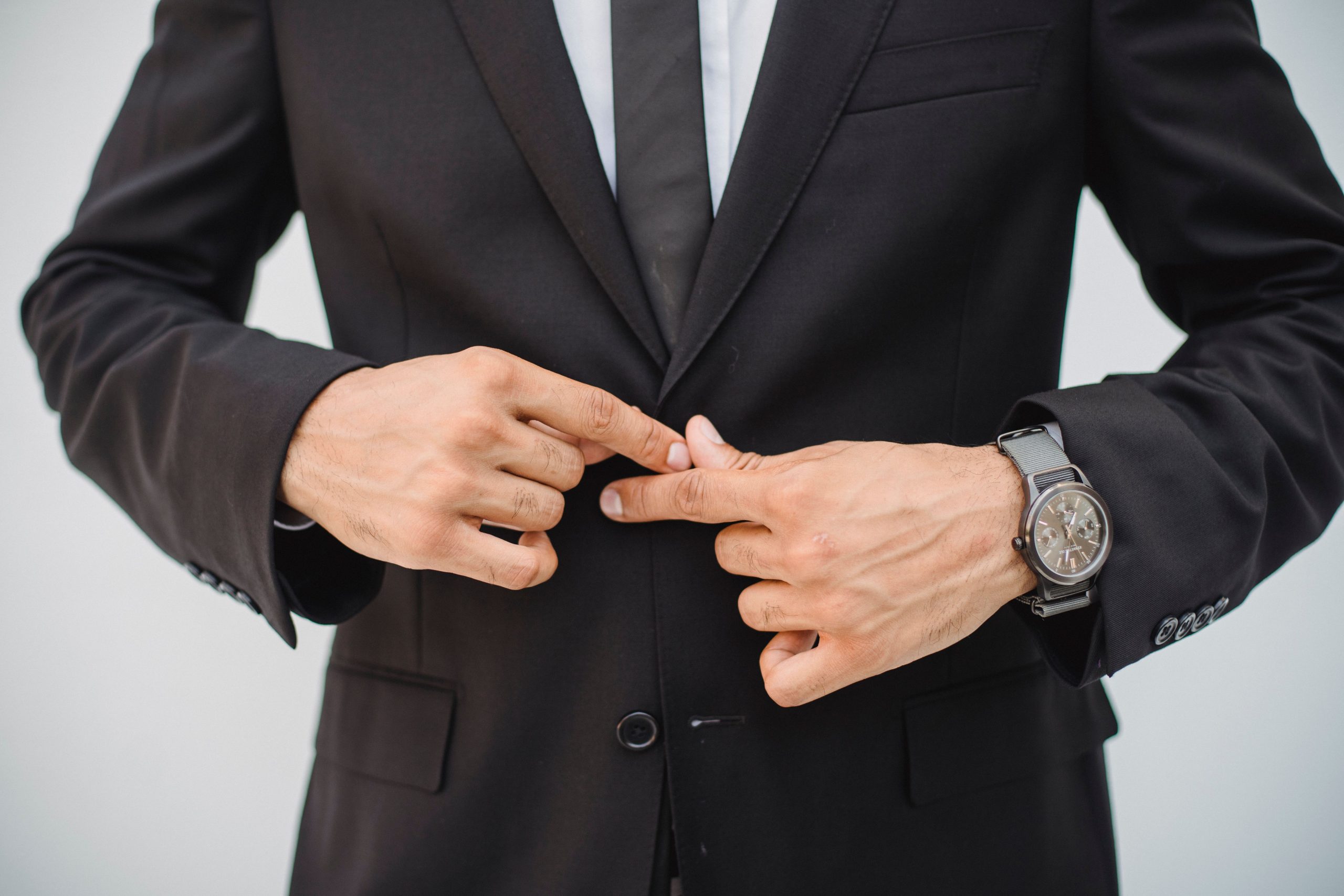 Hands buttoning a black suit coat